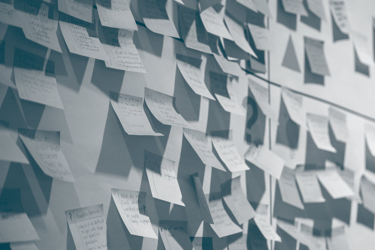 A wall covered on multiple sticky notes with handrwiting on them.